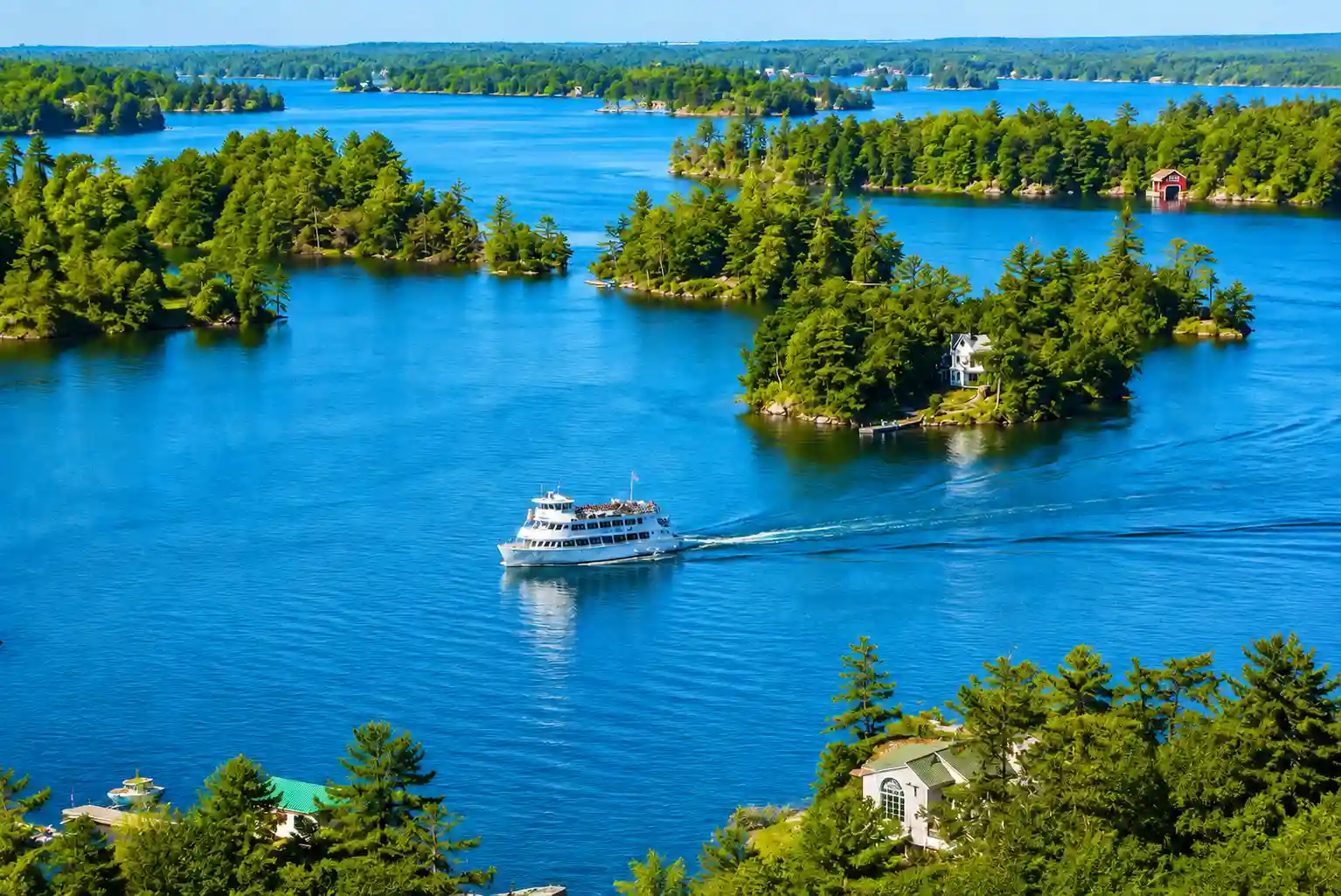 Stone castle with turrets on a small island in the St. Lawrence River seen from a passing cruise boat